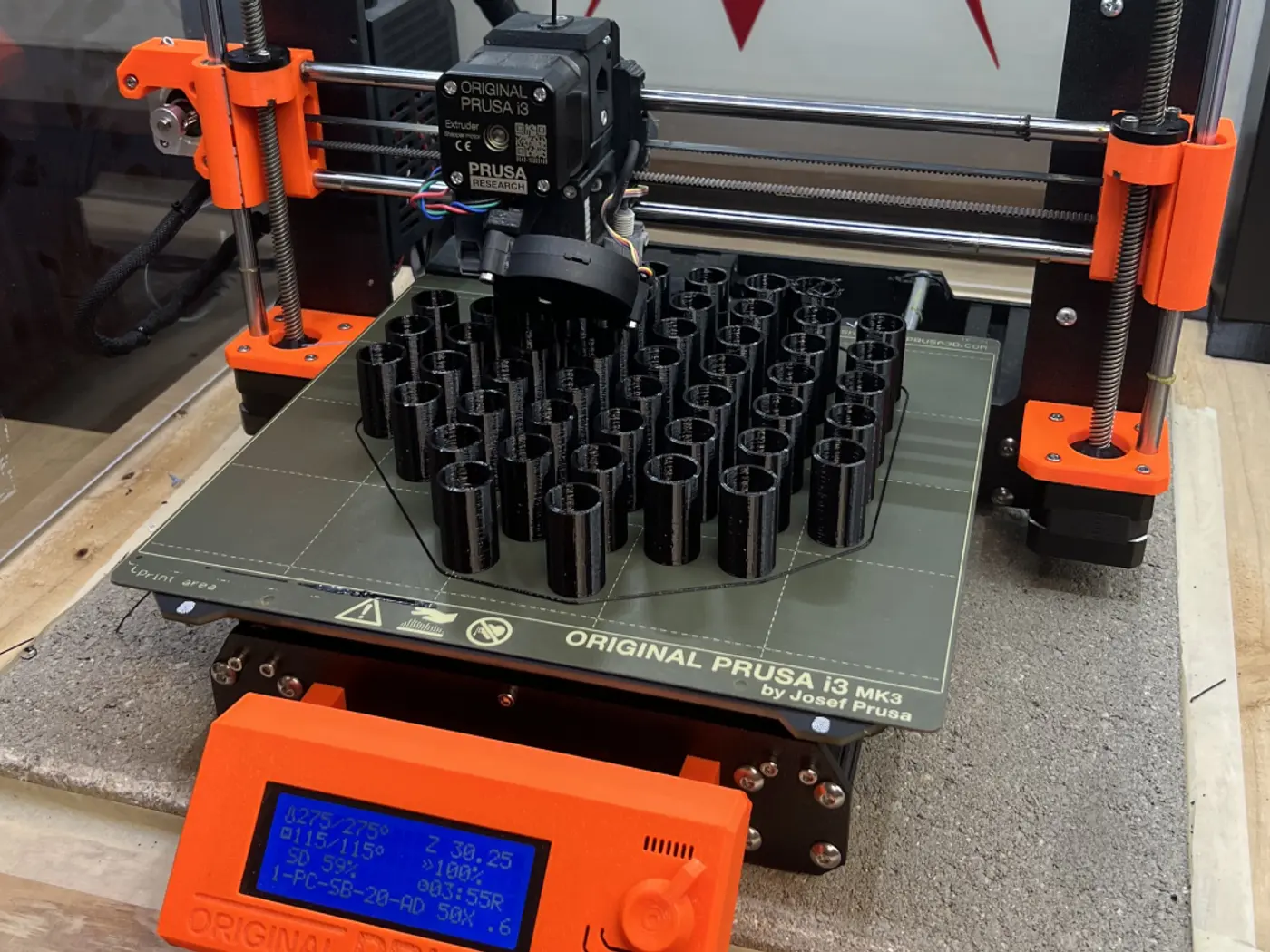 A printer mid-job, the bed full of black parts.