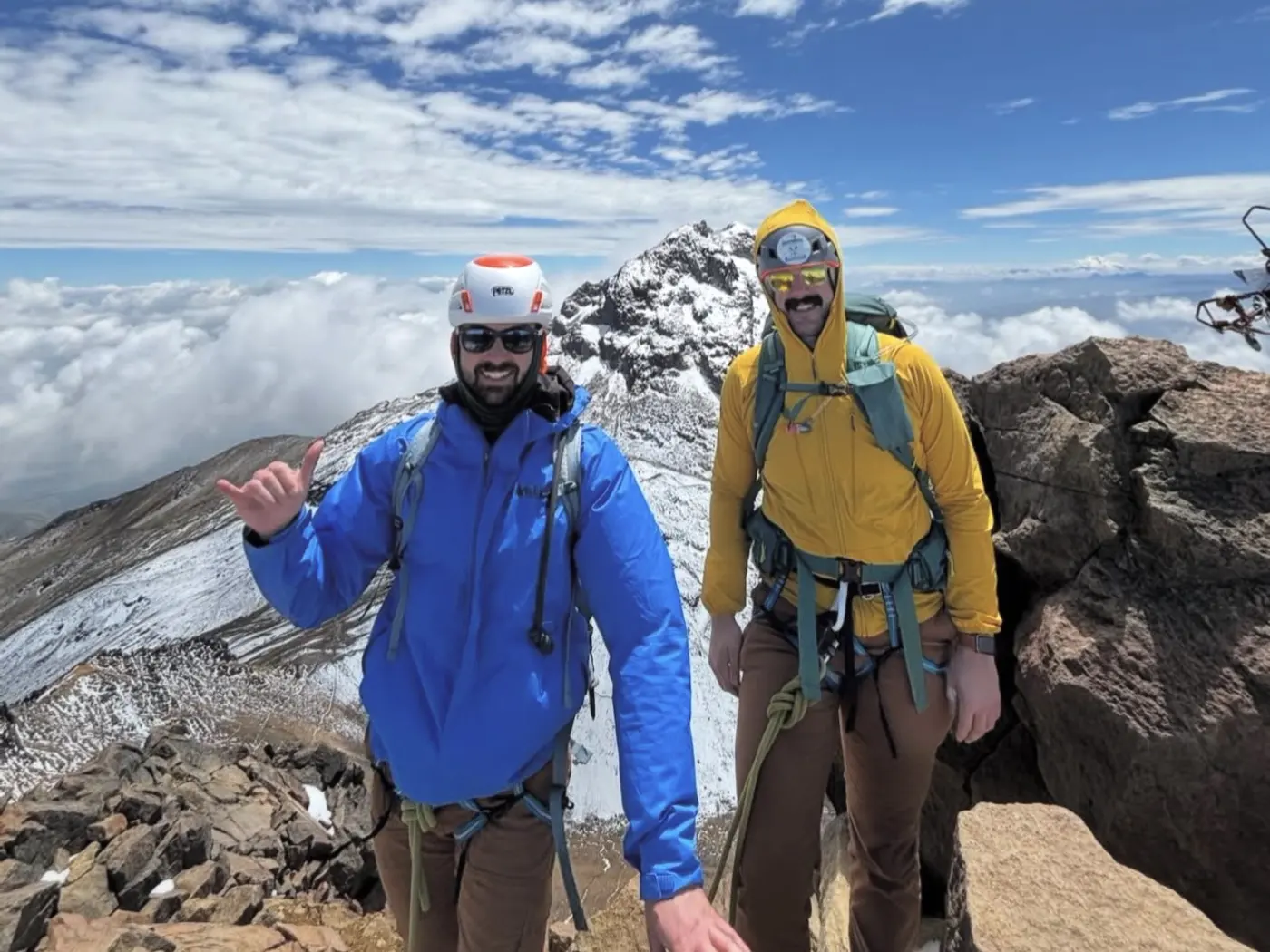Tim and a friend on a snowy summit above the clouds.