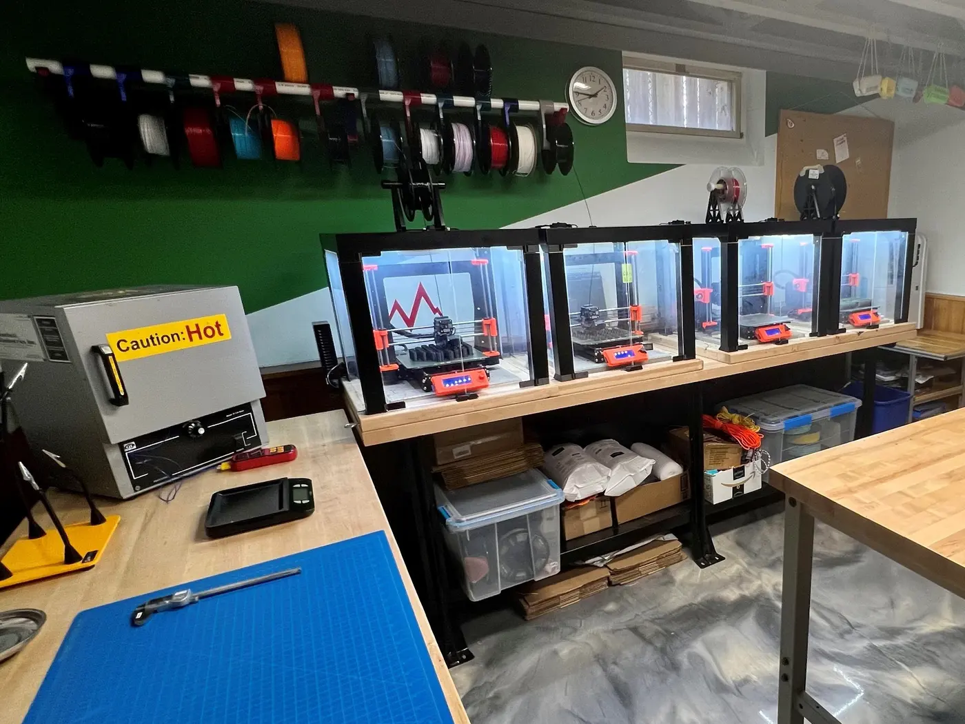 The Remote workshop in Tim's basement: a bank of printers, filament on the wall, and a curing oven.